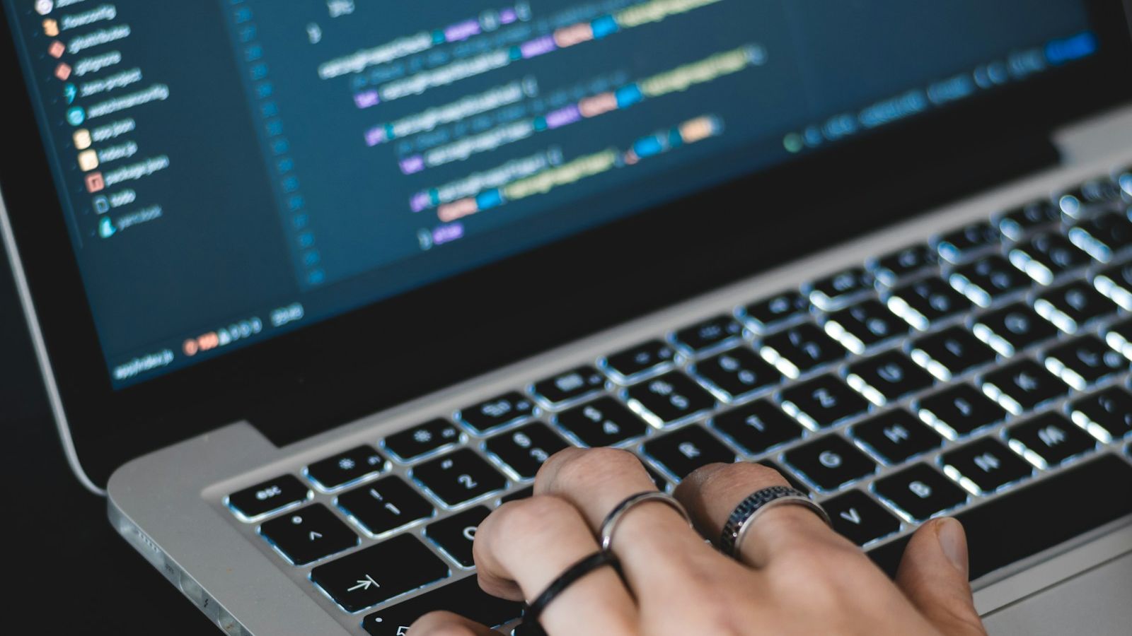 Hender som skriver på tastaturet til en bærbar PC med programkode på skjermen